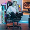 A young man is sitting in a gaming chair in a room with neon lighting. Voir les images du produit