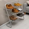 A shoe rack with various shoes and slippers on it, placed against a wall. Produktbild-Vorschau