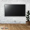 A modern living room with a wall-mounted TV and a plant. Anteprima dell’immagine prodotto