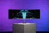 A curved gaming monitor displaying a futuristic race car is showcased on a pedestal against a gradient purple and blue background. Náhľad obrázku produktu
