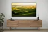 A modern living room setup with a large TV mounted above a wooden media console. Produktbild-Vorschau