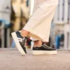 A person wearing white pants and black platform sneakers walks on a cobblestone street. Náhľad obrázku produktu