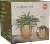 The image shows the packaging of a "Crying Plant Pot" with a spider plant in the pot. There is also a smaller inset image showing the pot with water dripping from the eyes. Produktbild-Vorschau