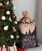 A Christmas sack with a festive design sits next to a decorated Christmas tree. Anteprima dell’immagine prodotto