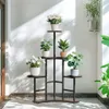 A multi-tiered plant stand filled with various potted plants is placed indoors near a window, with sunlight casting shadows on the wall. Náhľad obrázku produktu