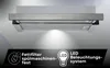 A kitchen range hood with a light illuminating downwards, set against a gradient background. A black banner at the bottom displays feature icons and text. Voir les images du produit