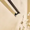 A close-up shot of a black metal handrail mounted on a light beige wall, with a shadow of branches and white flowers visible on the wall. Anteprima dell’immagine prodotto