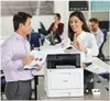 Two colleagues are interacting with a printer in an office setting. Anteprima dell’immagine prodotto