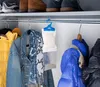 A closet interior with clothes hanging on a rod, and a dehumidifier bag hanging. Produktbild-Vorschau