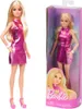 A Barbie doll in a pink dress is shown standing next to its packaging, which also features a picture of the doll. Podgląd zdjęcia produktu