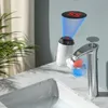 A close-up view of a faucet attachment with a digital display showing the water temperature, set against a bathroom sink and a plant. Produktbild-Vorschau