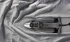 An iron is placed on a wrinkled gray fabric. Produktbild-Vorschau