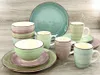 A collection of ceramic dishes and mugs in various pastel colors, arranged on a wooden surface. Produktbild-Vorschau