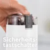 A hand is shown pressing a safety switch on a coffee grinder. Anteprima dell’immagine prodotto