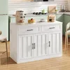 A white kitchen island with drawers and cabinets, set in a kitchen environment with a refrigerator, stove, and backsplash. Náhled obrázku produktu