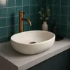 A modern bathroom sink setup with a speckled beige basin, copper faucet, and teal tiled wall. Produktbild-Vorschau