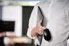 A person in a white shirt holds a laptop and a black computer mouse. Voir les images du produit