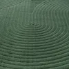 A close-up view of a green rug with a curved line pattern. Podgląd zdjęcia produktu