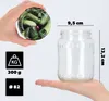 A hand holds a jar lid with a cucumber pattern, next to a clear glass jar with dimensions indicated. Below the jar are icons indicating weight and diameter. Podgląd zdjęcia produktu