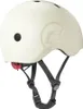 A cream-colored helmet with black straps and a red clip is shown against a white background. Náhled obrázku produktu