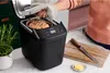 A person is taking a loaf of bread out of a bread maker in a kitchen setting. Náhľad obrázku produktu
