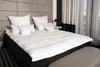 A neatly made bed with a white duvet and pillows. Produktbild-Vorschau