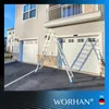 A silver telescopic ladder is set up in an A-frame position in front of a residential garage with two white doors. Produktbild-Vorschau