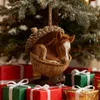 A Christmas ornament of a foal sleeping in an acorn, hanging from a Christmas tree, surrounded by wrapped gifts. Produktbild-Vorschau