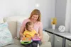 A woman and a child are sitting on a couch and playing with a toy book. Voir les images du produit