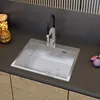 A modern kitchen sink with a black faucet, set against a dark gray backsplash and wooden cabinets. Produktbild-Vorschau