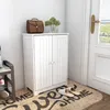 A white cabinet is placed in an entryway next to a door, with a doormat and slippers in front of it. Produktbild-Vorschau