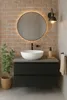 A modern bathroom vanity with a vessel sink, round mirror with LED lighting, and a wall-mounted faucet, set against a brick wall. Produktbild-Vorschau