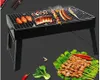 A portable charcoal grill with food cooking on it, and a plate of skewers and vegetables in the foreground. Produktbild-Vorschau