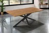 A dining table with a wooden top and a black spider-like base is shown in a room with large windows. Produktbild-Vorschau
