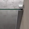 A close-up view of a shower wall corner with a glass panel and metal frame. Voir les images du produit