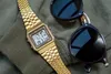 A gold Casio watch and black sunglasses are placed on a green fabric surface. Produktbild-Vorschau