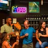 People at a bar with a neon sign. Voir les images du produit