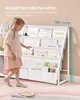 A young girl is reaching for a book on a white children's bookshelf. A height chart is visible on the right side. Produktbild-Vorschau