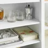 A close-up of a shelf on a white cabinet, displaying glasses, a coffee maker, and books. Produktbild-Vorschau