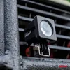 A close-up shot of a black work light attached to a metal structure. Produktbild-Vorschau