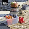 Storage boxes and fishing gear on a wooden dock by the water. Produktbild-Vorschau