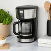 A coffee maker on a kitchen counter next to a plant and some books. Náhľad obrázku produktu