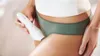 A person is holding a white electric epilator near their thigh. Náhľad obrázku produktu