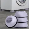 A washing machine is shown with anti-vibration pads underneath its feet. Several pads are also stacked in the foreground. Voir les images du produit