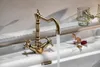 A vintage-style bronze faucet with water running into a white sink, with a dried leaf and flower nearby. Anteprima dell’immagine prodotto