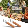 A group of people are enjoying a barbecue and meal outdoors, with a grill in the background and food and drinks on a table in the foreground. Produktbild-Vorschau