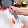 A hand holding a pan handle with a silicone sleeve, with small pots in the background. Anteprima dell’immagine prodotto