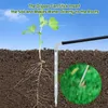 A plant seedling with its roots exposed, being watered by a solar-powered drip irrigation system. The system is shown inserting into the soil and delivering water directly to the roots, with a close-up inset showing the water droplets. Produktbild-Vorschau