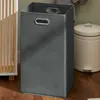 A dark gray laundry hamper is shown next to a light beige trash can, with a wooden cabinet in the background. Anteprima dell’immagine prodotto