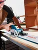 A person is using a circular saw on a wooden surface, with a partially assembled cabinet in the background. Voir les images du produit